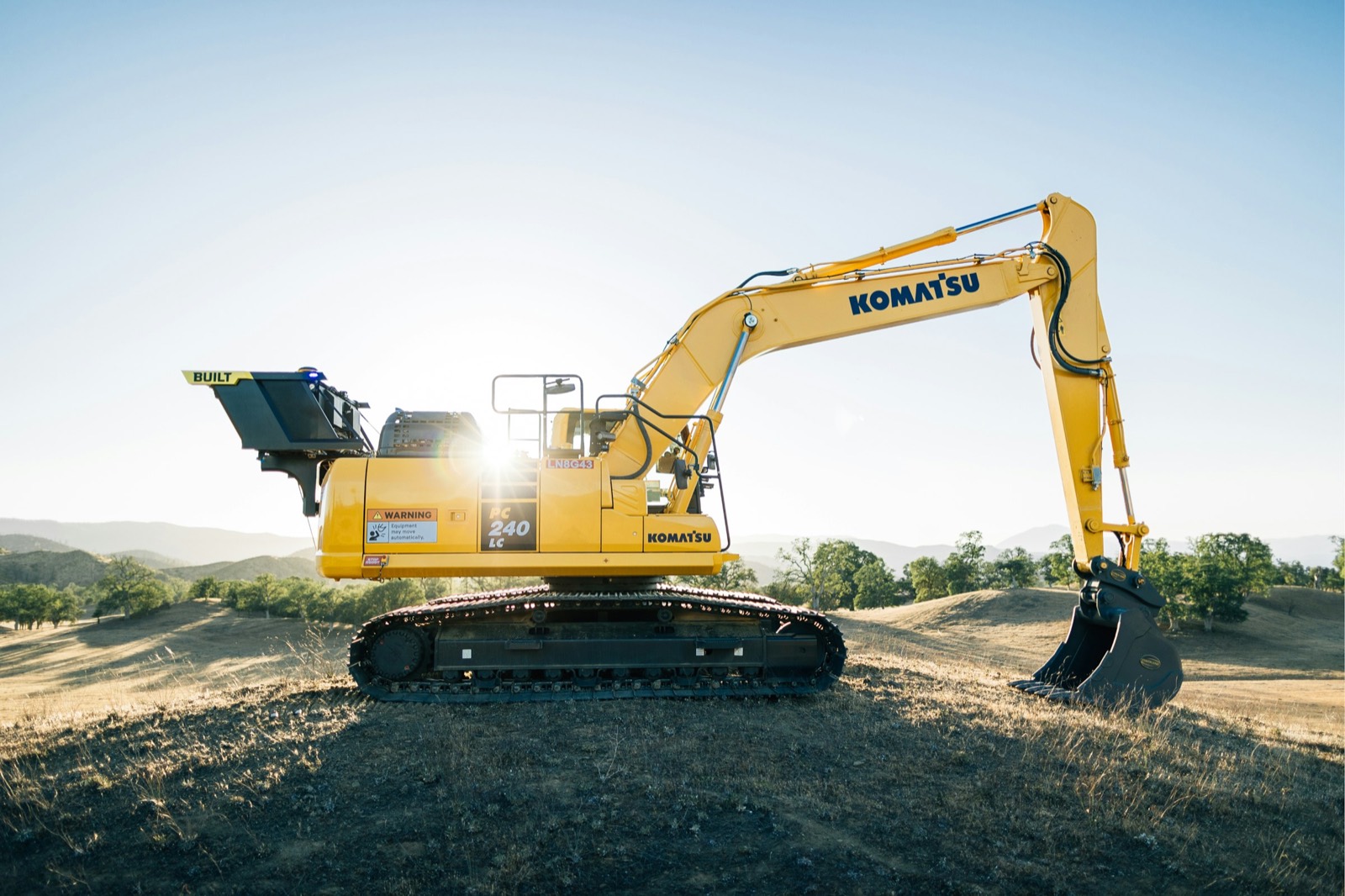 Autonomous excavator by Built Robotics working in an open field at sunrise